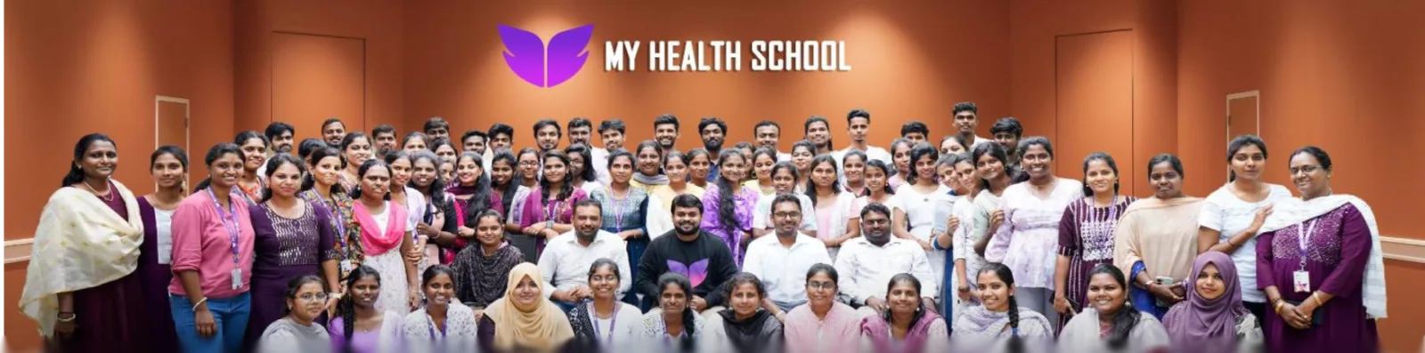 The My Health School team standing together under the brand wall